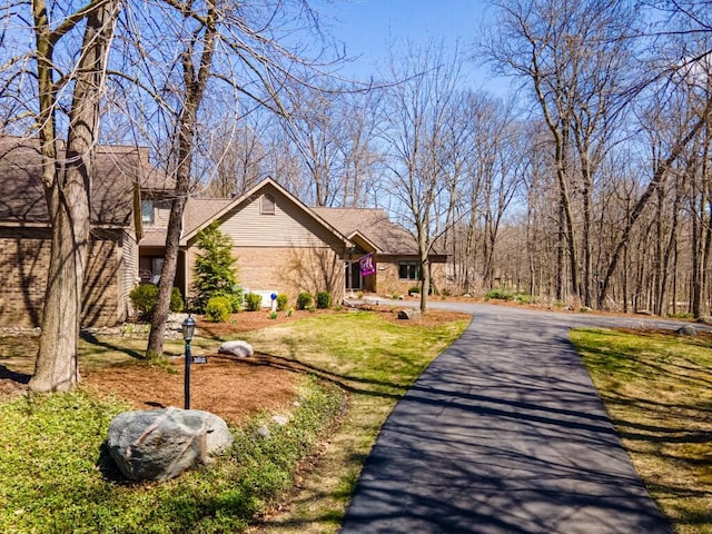 exterior space with brick siding, a front yard, and aphalt driveway
