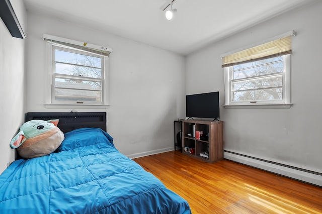 419 Larkspur Ave, Portage, MI 49002 - bedroom with a baseboard heating unit, baseboards, wood finished floors, and multiple windows
