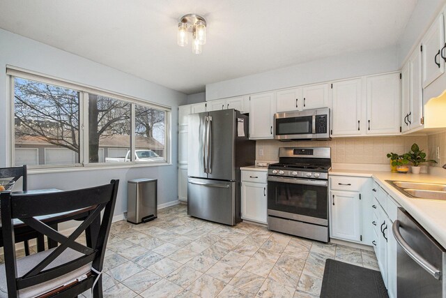 2420 E Collier Ave SE, Grand Rapids, MI 49546 - kitchen with stainless steel appliances, light countertops, white cabinets, backsplash, and a sink