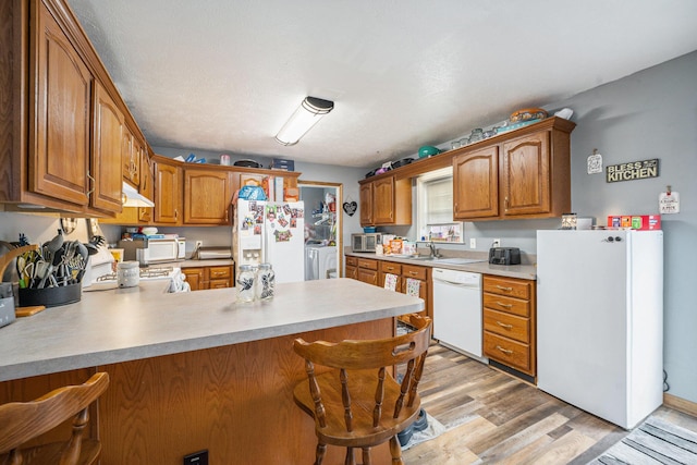 103 S Leeth St, White Pigeon, MI 49099 - kitchen with white appliances, washer and dryer, light countertops, a peninsula, and under cabinet range hood