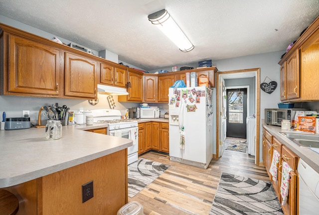 103 S Leeth St, White Pigeon, MI 49099 - kitchen featuring a textured ceiling, light wood-style floors, white appliances, brown cabinets, and under cabinet range hood