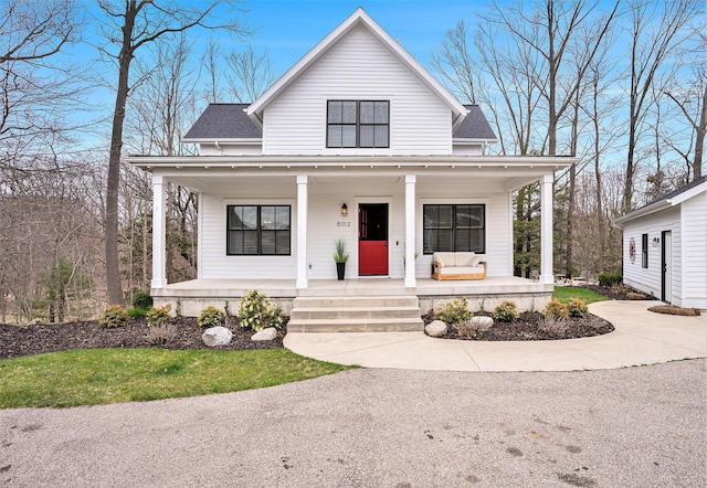 view of front facade featuring a shingled roof and covered porch