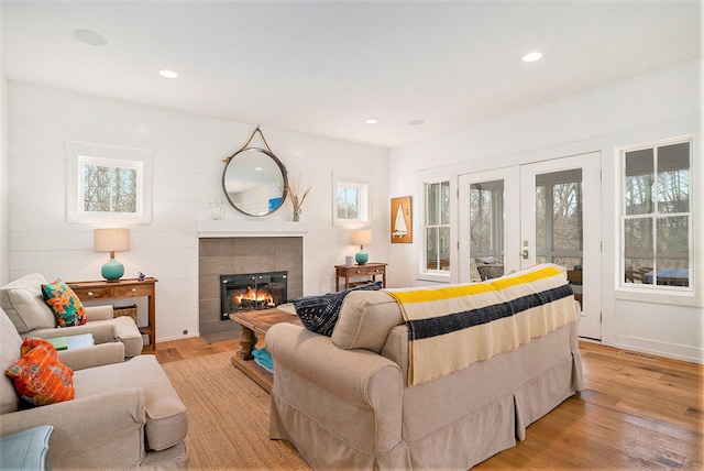 living room featuring french doors, light wood-type flooring, visible vents, recessed lighting, and a fireplace