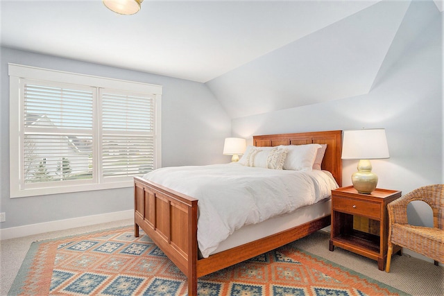 bedroom with vaulted ceiling, baseboards, and light colored carpet