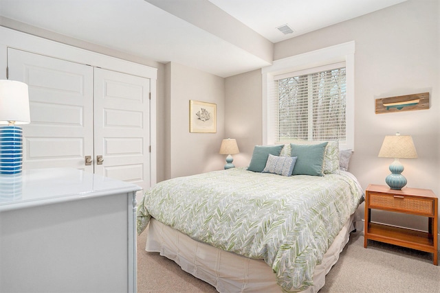 bedroom featuring light colored carpet, visible vents, and a closet
