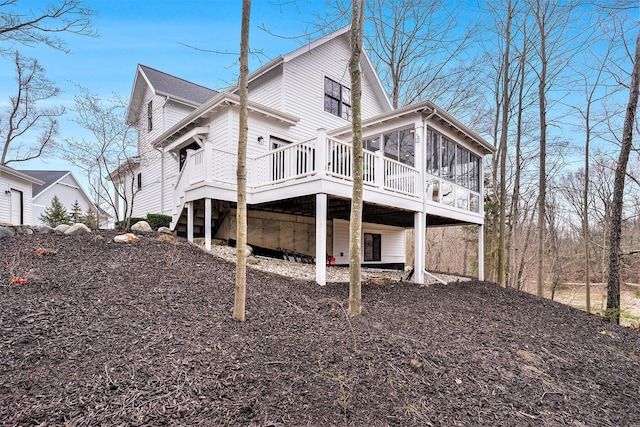 rear view of house with a wooden deck and a sunroom