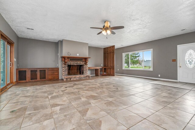 11886 Riverside Dr, White Pigeon, MI 49099 - unfurnished living room featuring a ceiling fan, a textured ceiling, baseboards, a brick fireplace, and visible vents