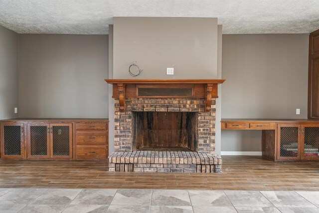 11886 Riverside Dr, White Pigeon, MI 49099 - unfurnished living room featuring a textured ceiling, wood finish floors, a brick fireplace, and baseboards