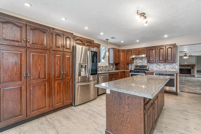 11886 Riverside Dr, White Pigeon, MI 49099 - kitchen with stainless steel appliances, a center island, a textured ceiling, backsplash, and under cabinet range hood
