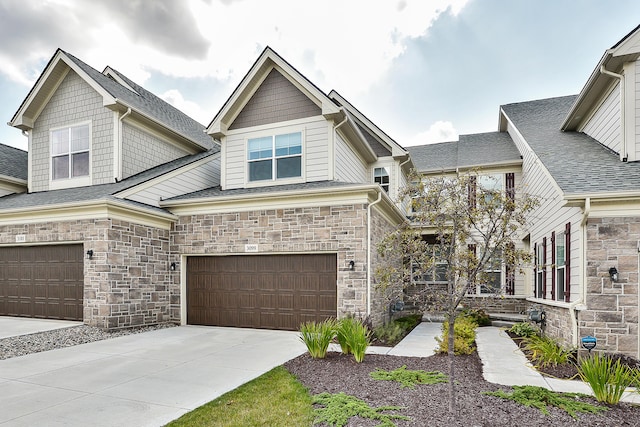 craftsman inspired home with concrete driveway, an attached garage, and stone siding