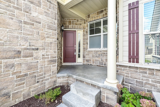 entrance to property featuring a porch and stone siding