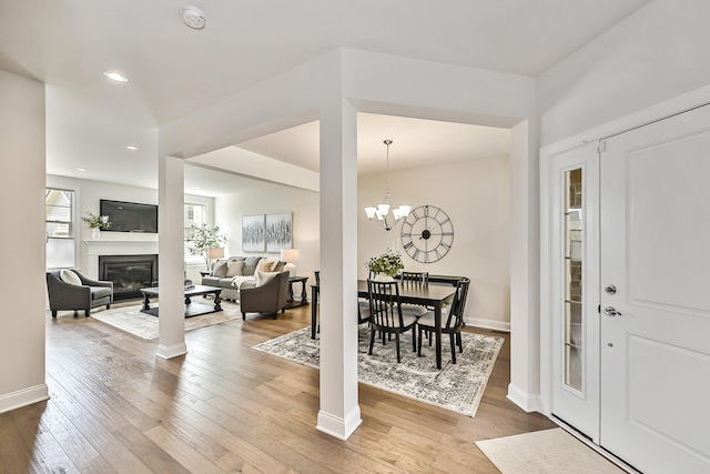 entrance foyer featuring recessed lighting, wood-type flooring, baseboards, a chandelier, and a glass covered fireplace