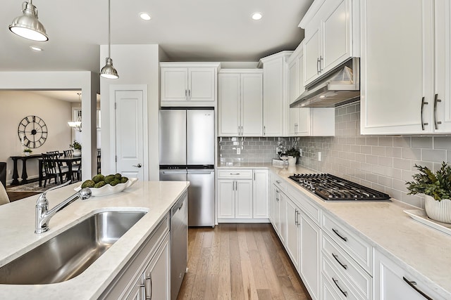kitchen featuring under cabinet range hood, stainless steel appliances, a sink, dark wood-style flooring, and white cabinetry