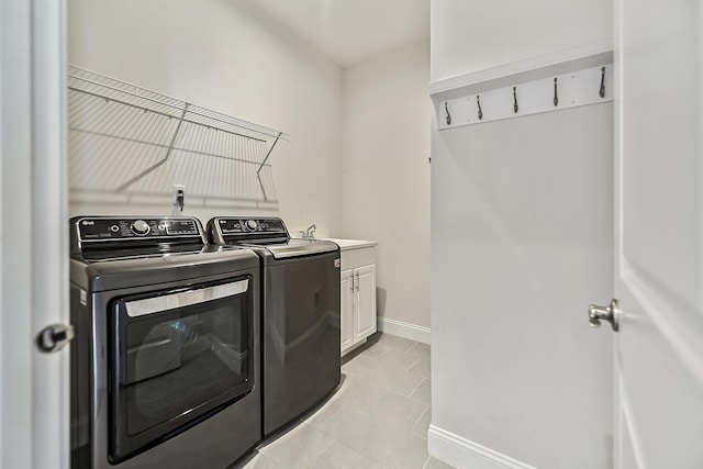 laundry room featuring cabinet space, washing machine and clothes dryer, baseboards, and light tile patterned flooring