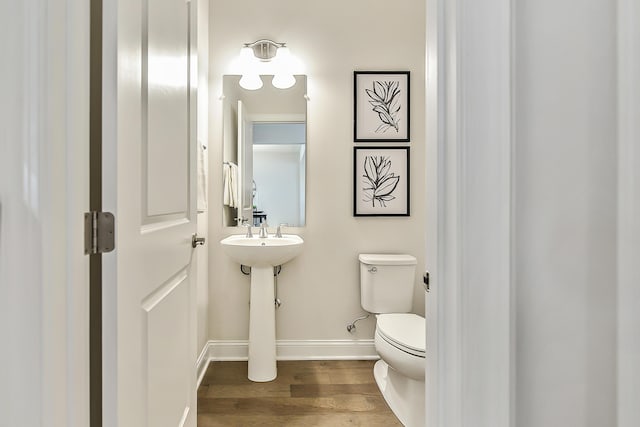 bathroom with baseboards, toilet, and wood finished floors