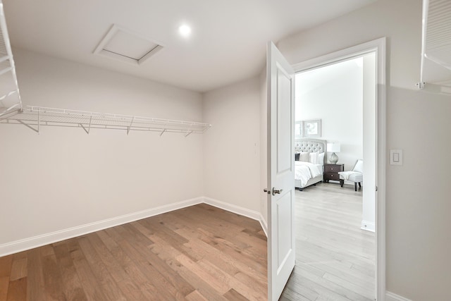 spacious closet with attic access and wood finished floors