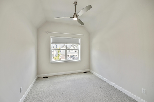 empty room featuring vaulted ceiling, ceiling fan, carpet floors, baseboards, and visible vents