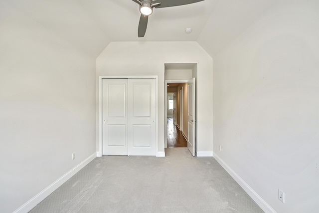 unfurnished bedroom featuring a closet, ceiling fan, carpet floors, baseboards, and lofted ceiling
