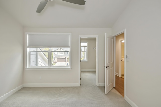 empty room featuring a ceiling fan, baseboards, and light carpet
