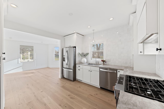 kitchen featuring light wood-style flooring, a sink, recessed lighting, white cabinetry, and appliances with stainless steel finishes