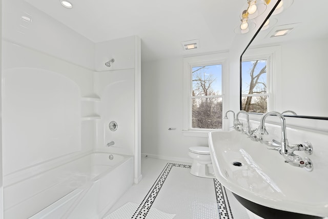 bathroom with washtub / shower combination, tile patterned flooring, toilet, a sink, and baseboards