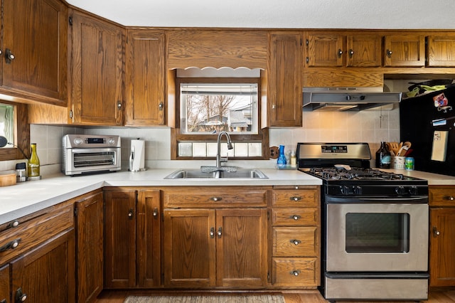 5505 Lakewood Dr, Coloma, MI 49038 - kitchen featuring a sink, tasteful backsplash, light countertops, under cabinet range hood, and stainless steel gas stove