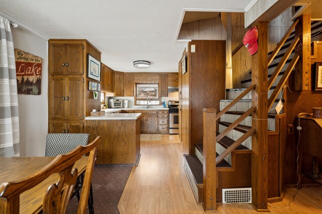 5505 Lakewood Dr, Coloma, MI 49038 - kitchen featuring a sink, brown cabinets, light wood-style floors, stainless steel range with gas stovetop, and visible vents