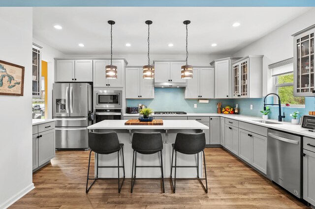 5849 Gavin Ln, Kalamazoo, MI 49009 - kitchen with a breakfast bar area, a center island, a sink, stainless steel appliances, and gray cabinets