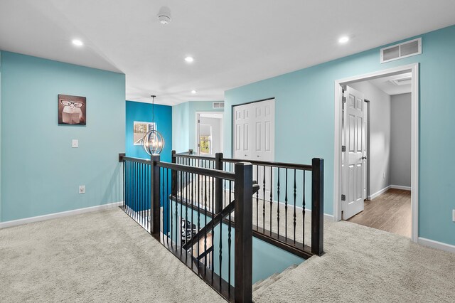 5849 Gavin Ln, Kalamazoo, MI 49009 - hallway featuring an upstairs landing, visible vents, an inviting chandelier, carpet floors, and baseboards