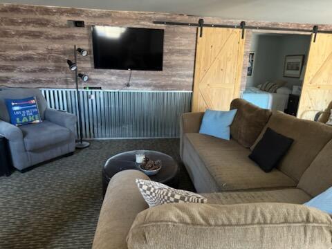 4605 Hunters Trl, Six Lakes, MI 48886 - living area featuring a barn door and carpet flooring
