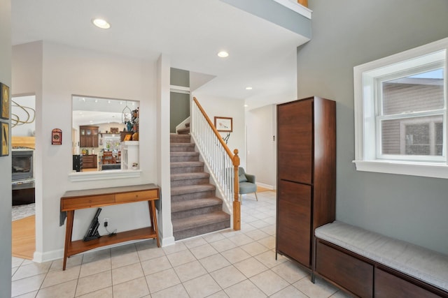 foyer entrance featuring baseboards, stairs, and light tile patterned floors