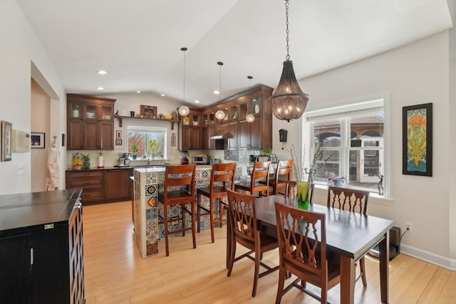 dining space with vaulted ceiling, light wood finished floors, baseboards, a notable chandelier, and recessed lighting
