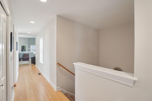 hallway featuring an upstairs landing, light wood-style floors, baseboards, visible vents, and recessed lighting