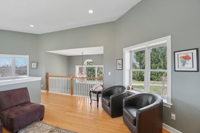 living room featuring an inviting chandelier, light wood-style flooring, a wealth of natural light, and a high ceiling