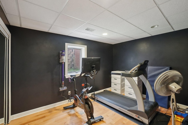 exercise area featuring wood finished floors, recessed lighting, baseboards, visible vents, and a paneled ceiling