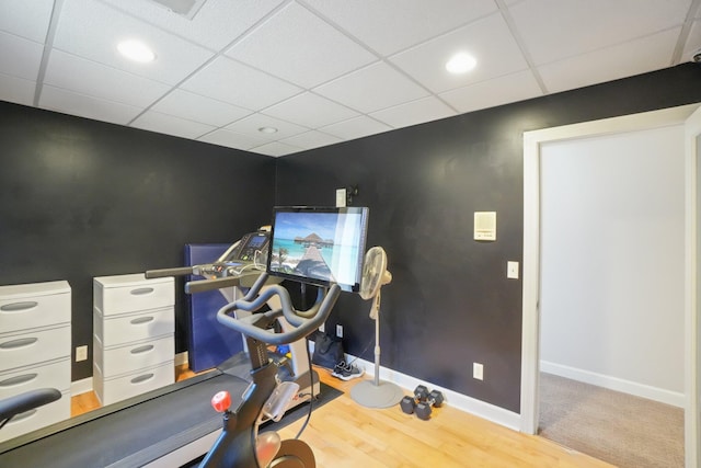 exercise area with wood finished floors, a drop ceiling, and baseboards