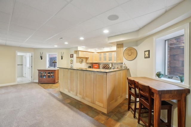 kitchen with light brown cabinets, a drop ceiling, glass insert cabinets, a peninsula, and recessed lighting