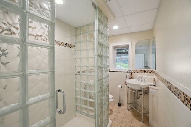 bathroom featuring tile patterned floors, a sink, toilet, tile walls, and a shower stall