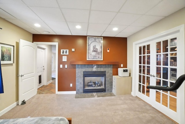 carpeted living room with recessed lighting, a paneled ceiling, a fireplace, and french doors