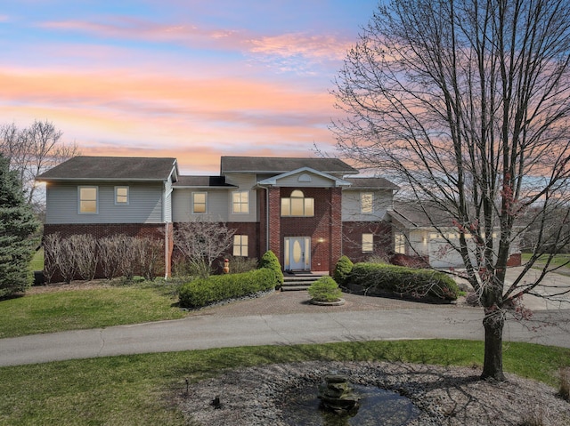 view of front of home featuring brick siding and a yard