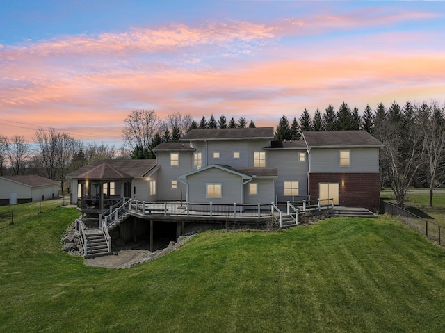 back of house at dusk featuring a fenced backyard, a wooden deck, and a yard