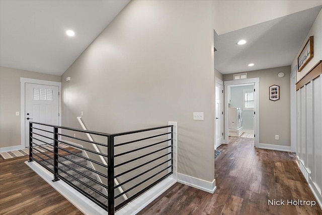 hallway with baseboards, dark wood-style floors, and an upstairs landing