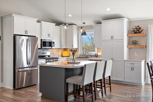 kitchen featuring white cabinets, tasteful backsplash, open shelves, a kitchen island, and appliances with stainless steel finishes