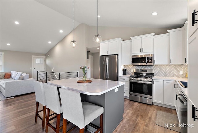 kitchen with tasteful backsplash, open floor plan, a breakfast bar area, stainless steel appliances, and a kitchen island