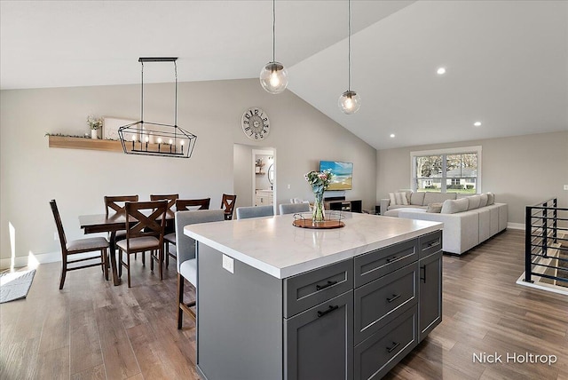 kitchen with light countertops, vaulted ceiling, a notable chandelier, and wood finished floors