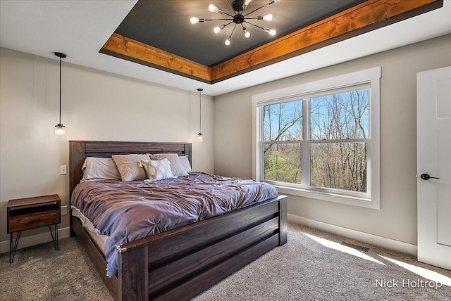 carpeted bedroom with baseboards, a chandelier, and a raised ceiling