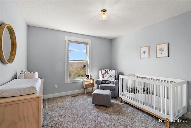 bedroom featuring a crib, baseboards, and carpet