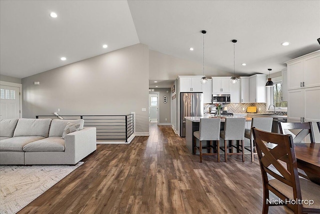 living area with recessed lighting, vaulted ceiling, a healthy amount of sunlight, and dark wood-style floors