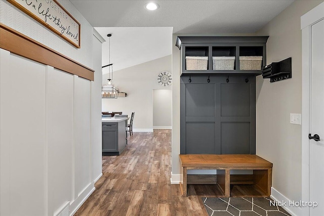 mudroom with visible vents, wood finished floors, baseboards, and vaulted ceiling