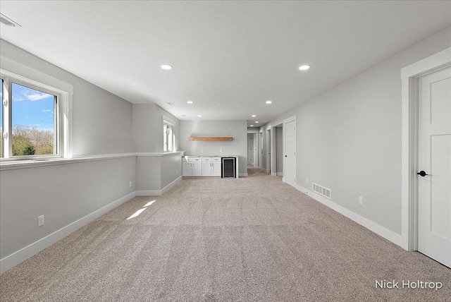 unfurnished living room featuring baseboards, light carpet, visible vents, and recessed lighting